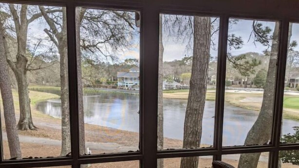Ein Zimmer mit großem Fenster, Blick auf einen See und einen Golfplatz.