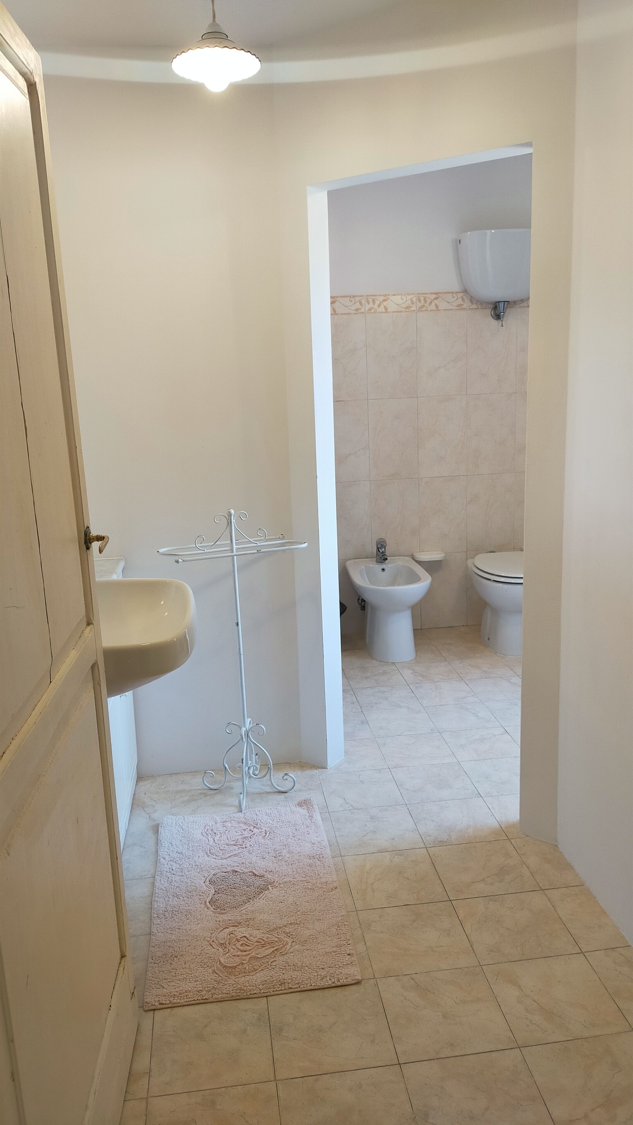 A bathroom with a sink, bidet, toilet, and a shower area.