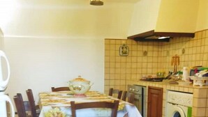 Een eethoek met een tafel gedekt voor vier personen, een wasmachine en een plafondventilator.