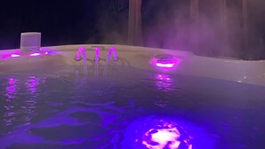Un bain à remous doté d’un éclairage violet, entouré d’une structure en bois.