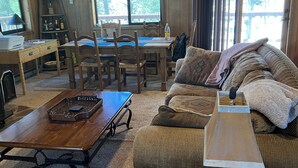 L’intérieur d’un chalet chaleureux, avec une table à manger en bois, des chaises, un canapé et une table basse.