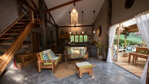 A spacious living area with a wooden staircase, a round dining table, and a cozy seating arrangement. - Villas Sampaguita (El Nido)