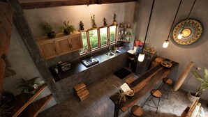A modern kitchen with wooden cabinets, a central island, bar stools, and potted plants. - Villas Sampaguita (El Nido)