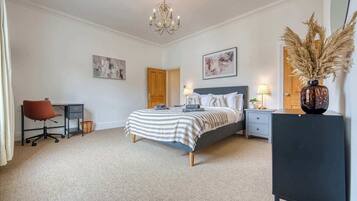 A bedroom with a bed, desk, chair, and a dresser.