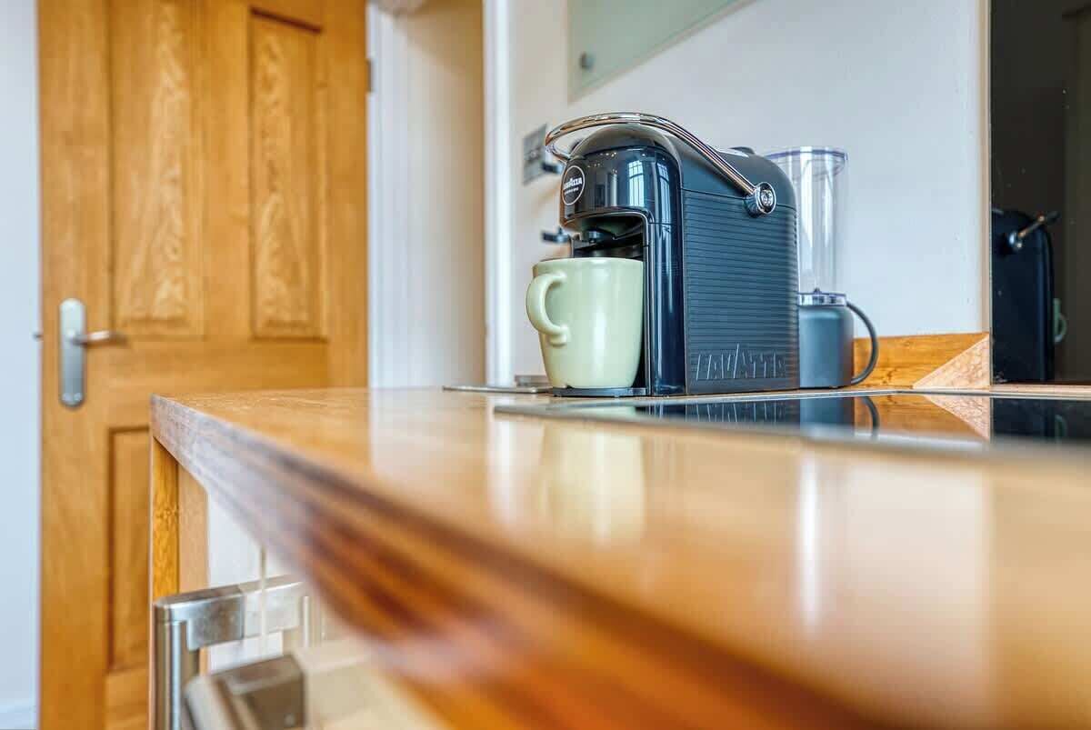Eine Kaffeemaschine auf einer Arbeitsplatte, mit Tasse und Krug.