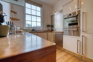 A modern kitchen with a wooden countertop, stainless steel appliances, and a window providing natural light.