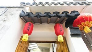 Une entrée de style architectural chinois traditionnel, avec des poutres en bois et des lanternes rouges.