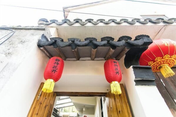A traditional Chinese architectural entrance with wooden beams and red lanterns. - Jingdaihuakai Inn (Suzhou)