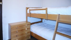 A bunk bed with a wooden dresser beside it.