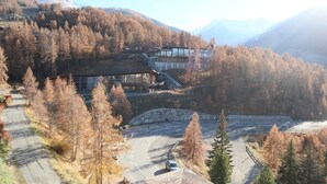A mountain lodge with a ski lift, surrounded by autumn trees and a parking area.