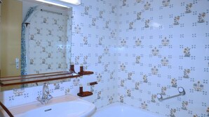 A bathroom with a sink, mirror, and bathtub.
