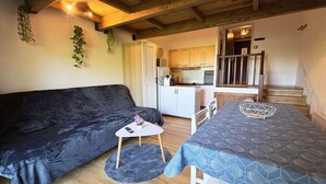 Un espacio habitable compacto con sofá, una mesita, una mesa de comedor y una cocina.