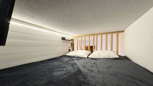 Una habitación con una cama individual superpuesta, un cabecero de madera y una pared blanca con textura.