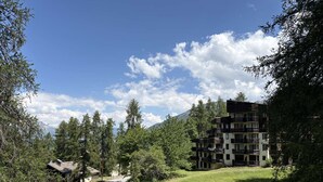 A multi-story building with balconies, surrounded by trees and a clear sky. - 12 LA Seille Studio 4 Personnes (LES ORRES 1650)