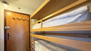 A bunk bed room with a wooden door and a light fixture above it. - 12 LA Seille Studio 4 Personnes (LES ORRES 1650)