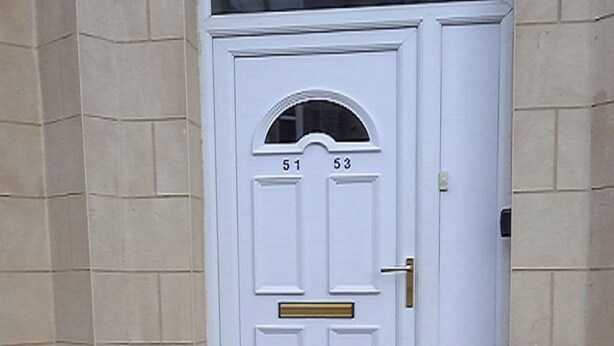 Una porta bianca con i numeri 51 e 53, una piccola finestra sopra e una maniglia in ottone.