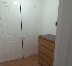Una habitación con armario, cómoda y puerta.