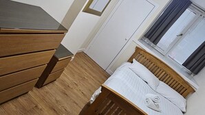 Una camera da letto con un letto di legno, una cassettiera, uno specchio e una finestra con tende.