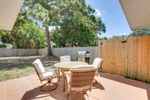 A patio with a round table and four chairs, a grill, and a wooden fence. - Dog-Friendly Home w/ Patio & BBQ in Bradenton (Bradenton)