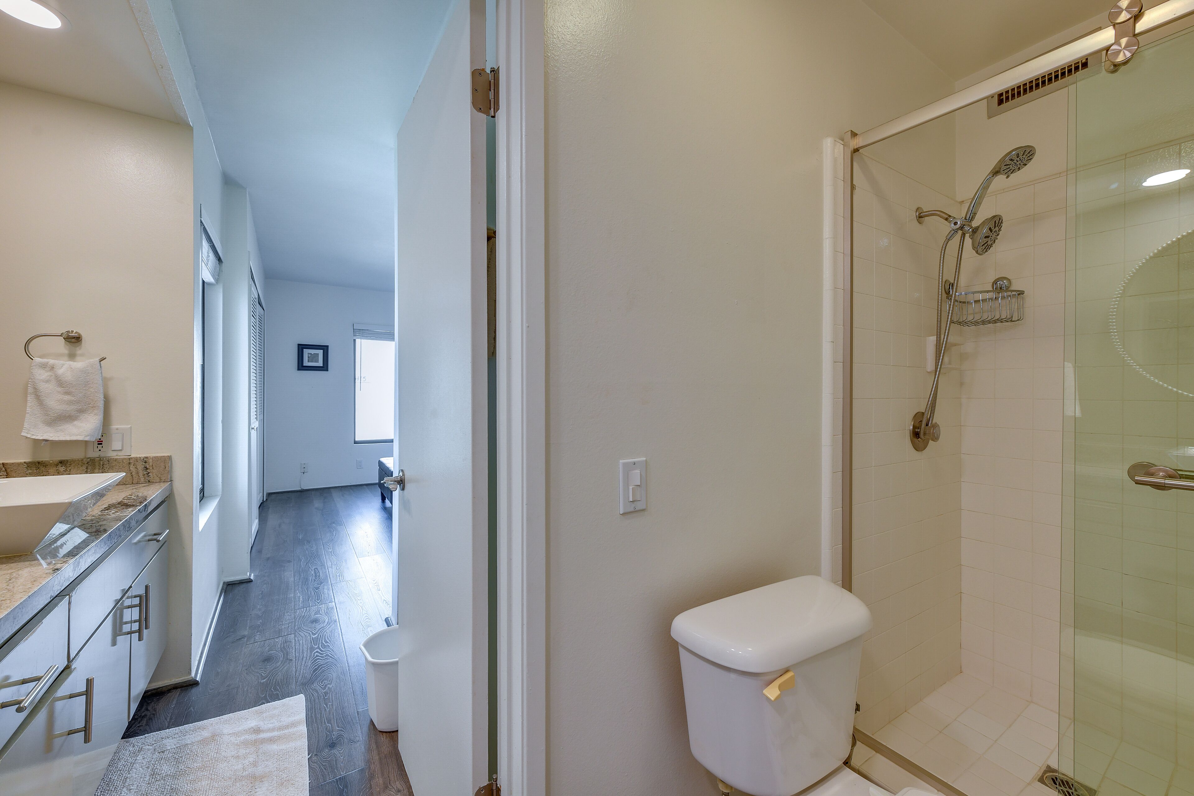 Un baño moderno con cabina de ducha de vidrio, inodoro blanco y tocador con espejo.