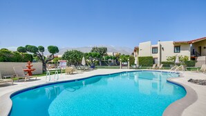 Une piscine à bord incurvé, entourée de chaises longues et d’une clôture.