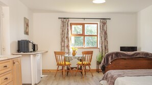 A cozy room with a bed, a desk, a chair, and a window with curtains.