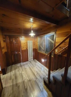 Staircase leads to an upper level in this spacious room with a door, window, and ceiling fan.
