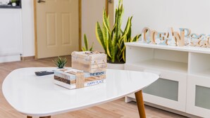Una mesa blanca con un control remoto, una pila de libros y una planta en maceta.