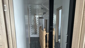A hallway with a wooden floor, a glass door, and a staircase with wooden balusters. - House - Sleeps 6 - Garden - Seaside - Pet Friendly (Great Yarmouth)