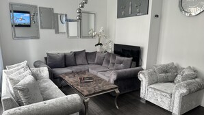 A modern living room with a sectional sofa, a coffee table, and decorative mirrors. - House - Sleeps 6 - Garden - Seaside - Pet Friendly (Great Yarmouth)