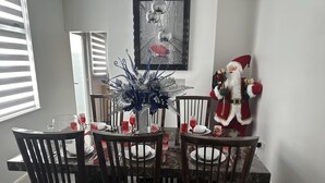 A dining table set for four with dark wooden chairs, a decorative centerpiece, and a Santa Claus figure on the right. - House - Sleeps 6 - Garden - Seaside - Pet Friendly (Great Yarmouth)