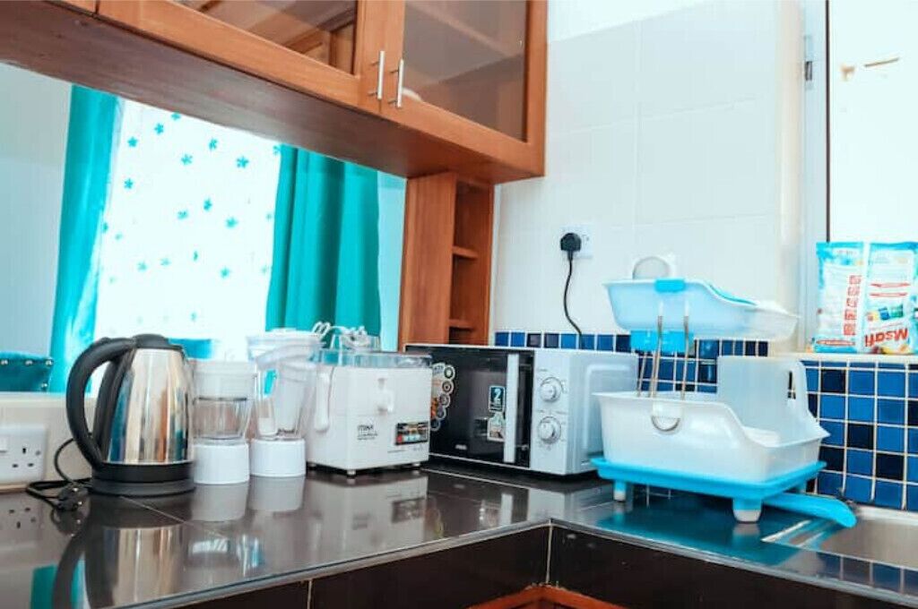 A kitchen with a kettle, toasters, a blender, and a blue water dispenser.