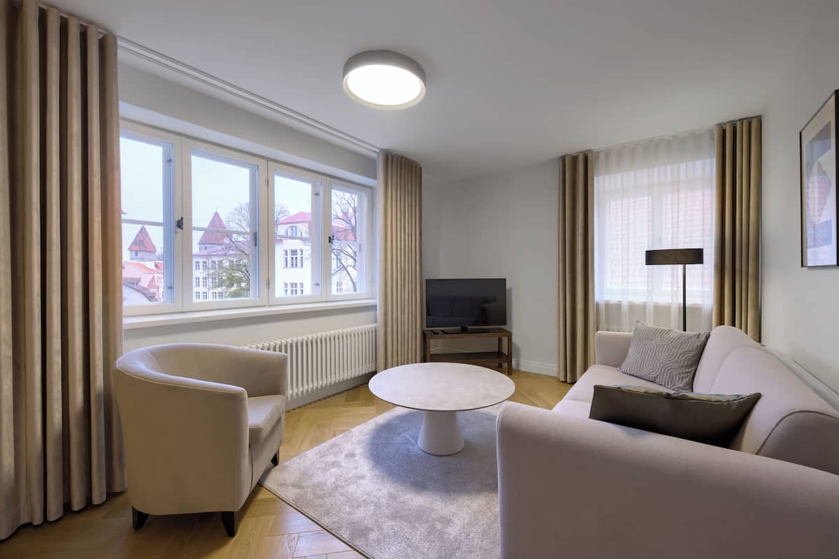 Ein modernes Wohnzimmer mit Sofa, Sessel und rundem Couchtisch.