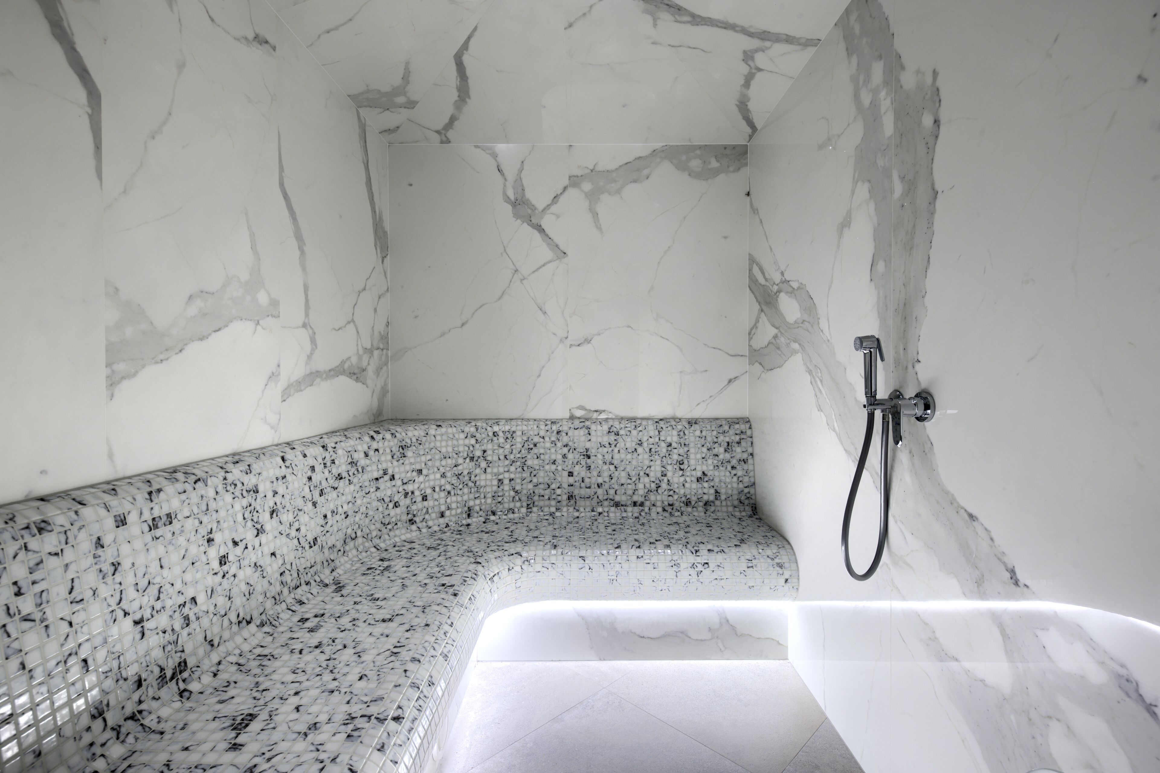 A bathroom with a marble wall, a shower, and a bathtub.