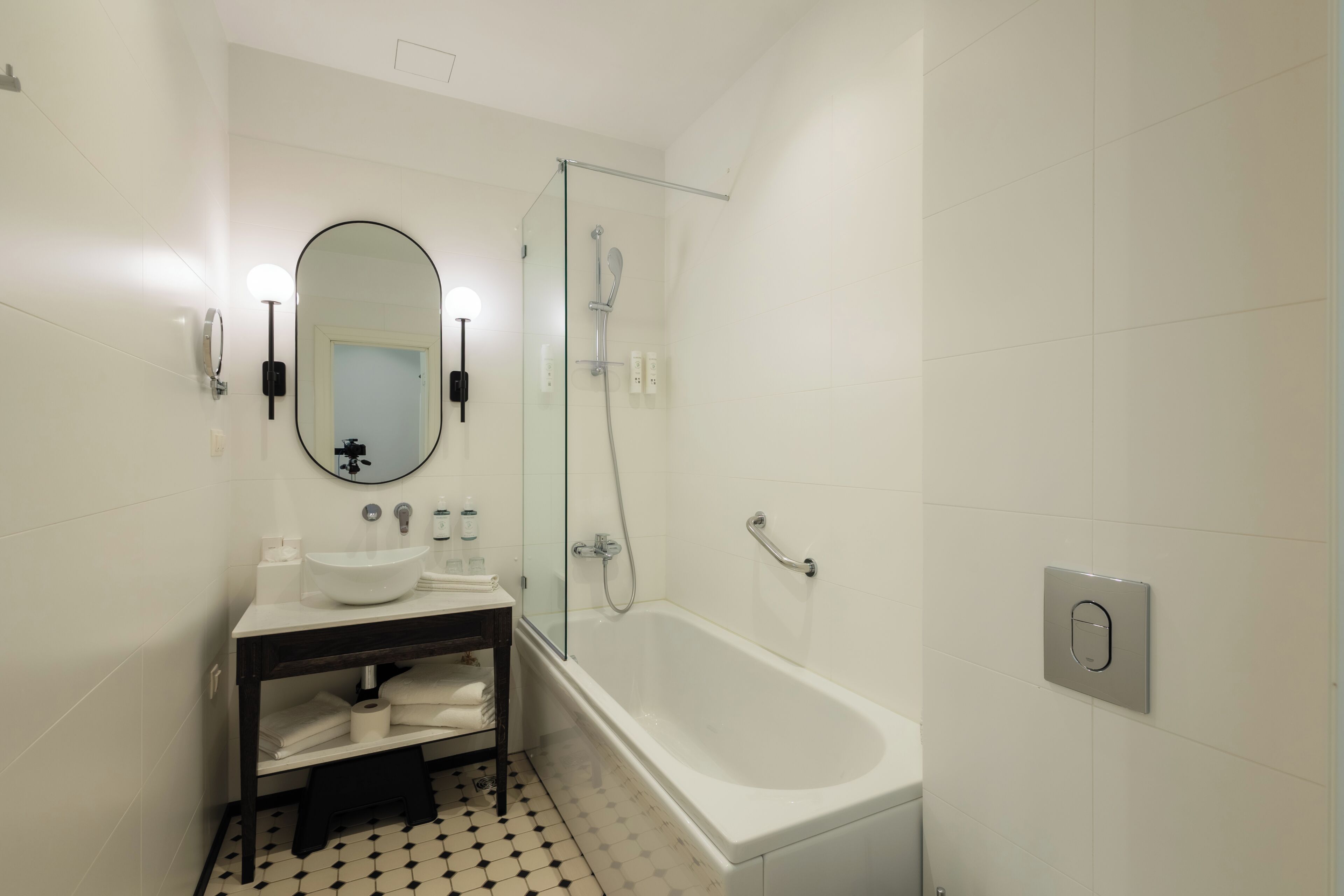 Un baño moderno con lavamanos blanco, espejo y ducha con cerramiento de vidrio.