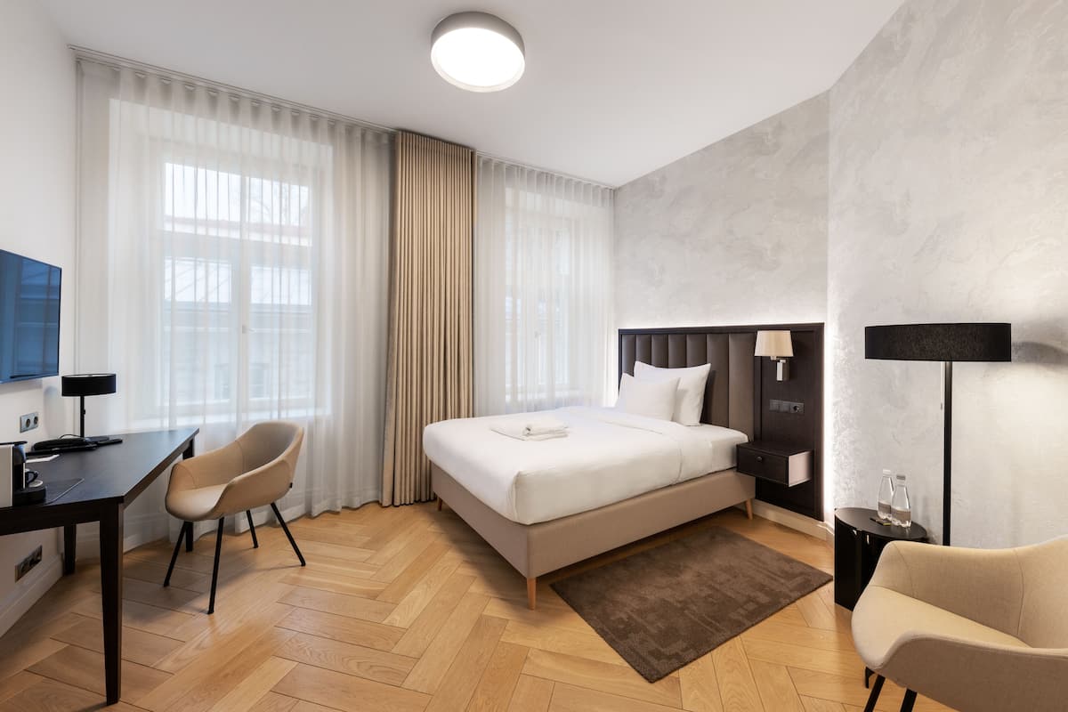 Ein modernes Hotelzimmer mit Bett, Schreibtisch, Stuhl, Fernseher und Lampe.