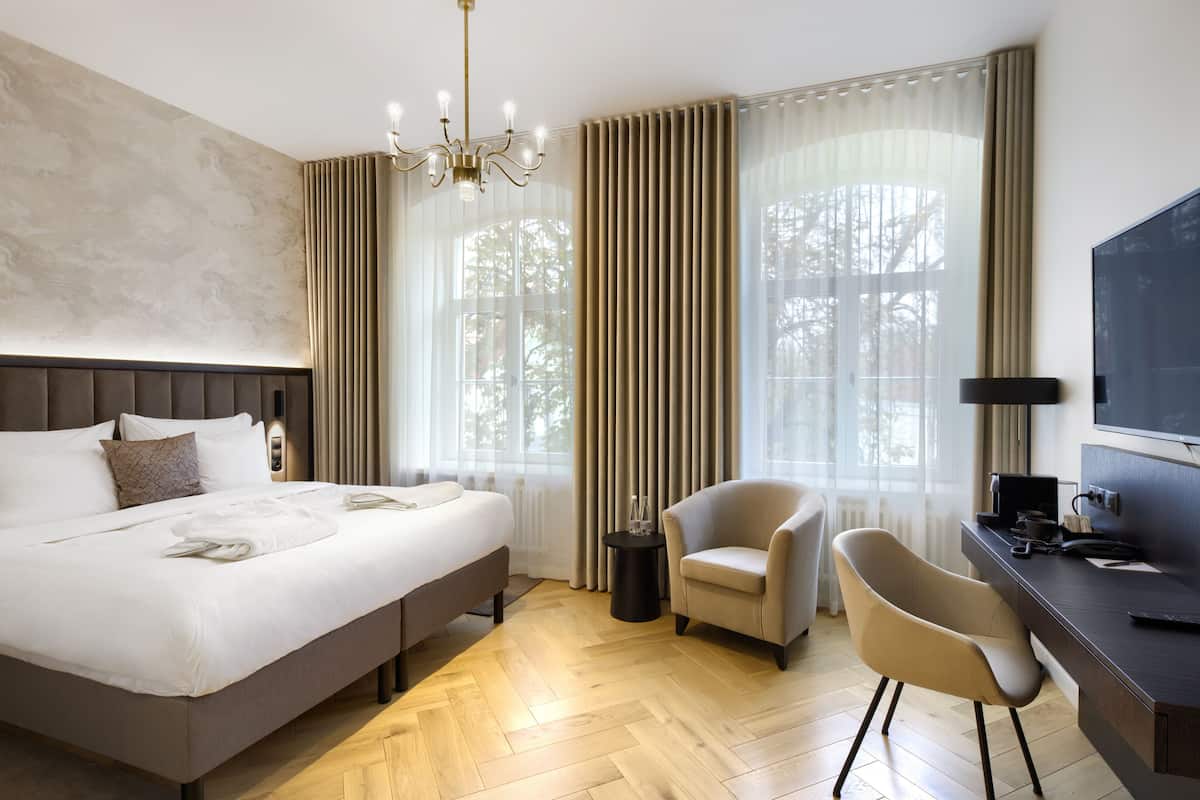 Ein modernes Hotelzimmer mit einem großen Bett, einem Schreibtisch, einem Stuhl und einem Fernseher.