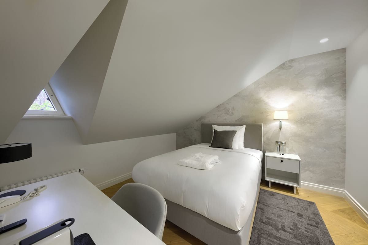 Ein modernes Schlafzimmer mit Bett, Nachttisch, Lampe und Schreibtisch mit Stuhl.