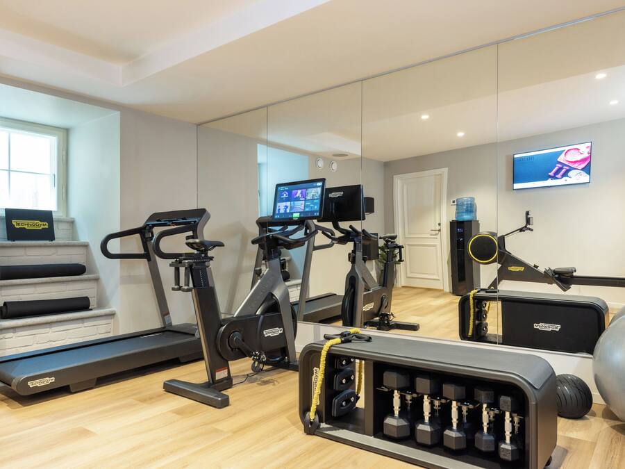 A home gym with treadmills, stationary bikes, a rowing machine, and a set of dumbbells.