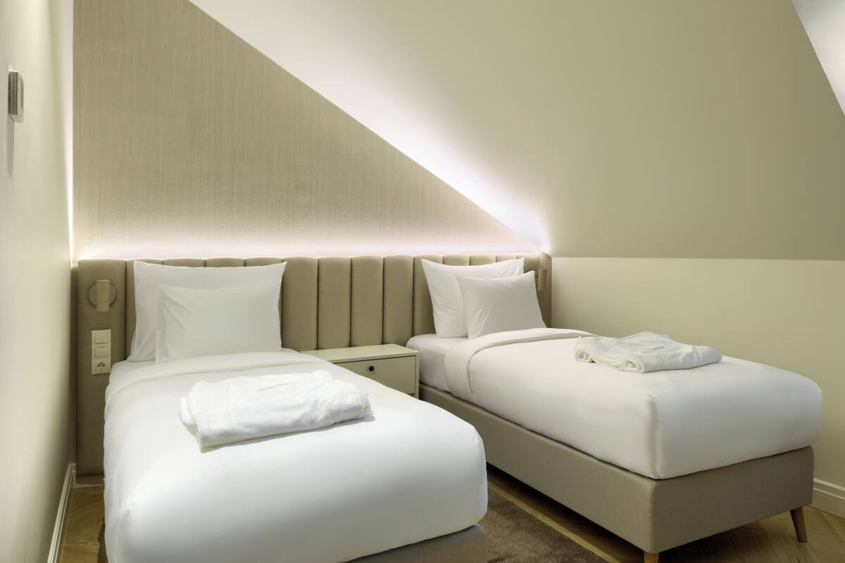 Ein modernes Hotelzimmer mit zwei Betten, einem großen Fenster und einer festen Kopfteil.