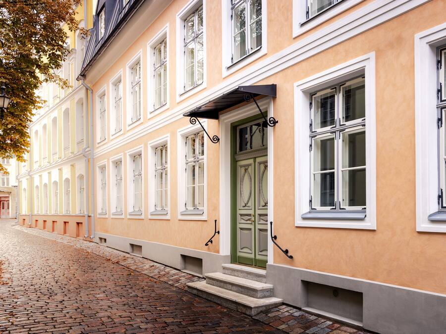 Ein Gebäude mit grüner Tür, weißen Fensterrahmen und einer Kopfsteinpflasterstraße.
