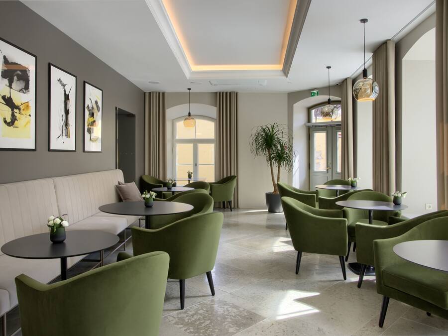 A modern interior with green upholstered chairs, round tables, and artwork on the walls.