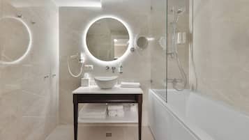 Un baño moderno con un espejo redondo, un lavabo, una bañera y una ducha.