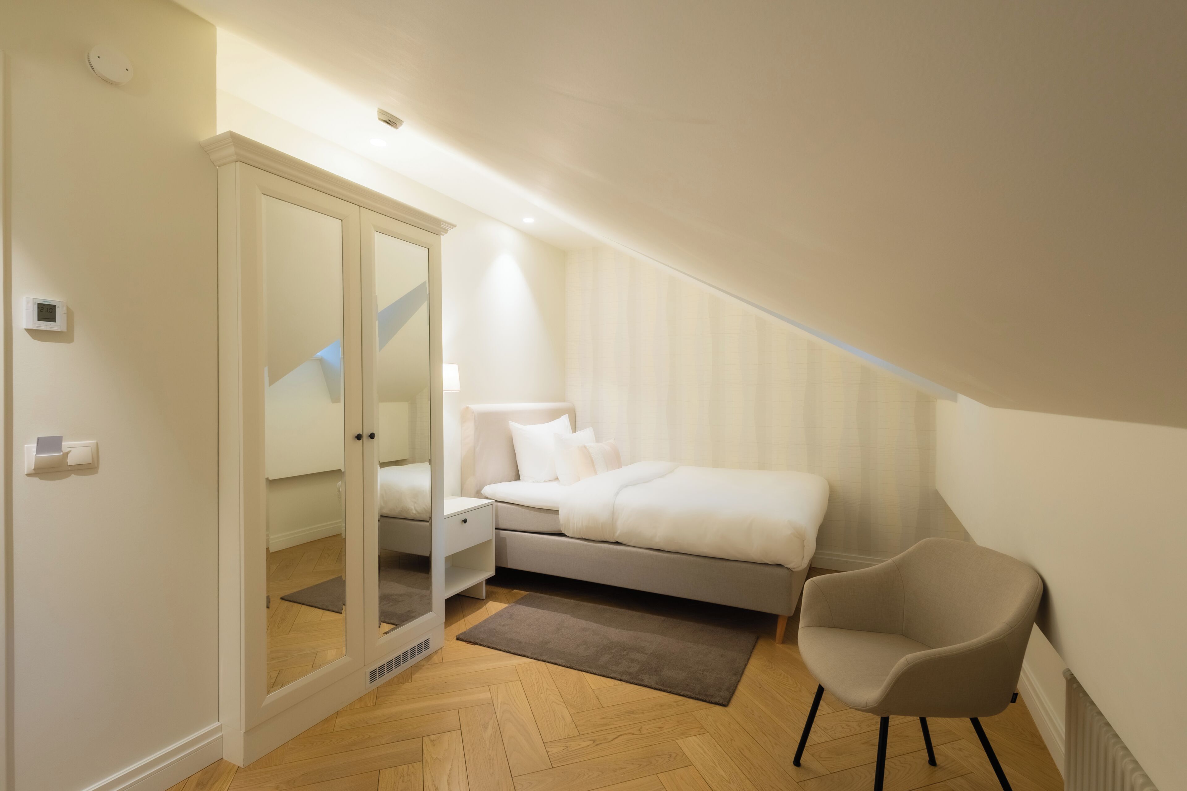 Un dormitorio con cama, una silla, un espejo y un radiador.