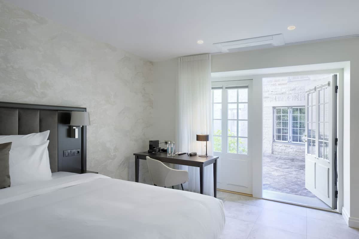 Ein Hotelzimmer mit Bett, Schreibtisch und Blick auf den Innenhof.