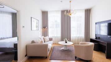 A modern hotel room with a sofa, a small table, a TV, and a bed.