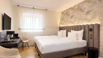 Habitación de hotel moderna con una cama grande, un escritorio con computadora, una silla y un televisor.