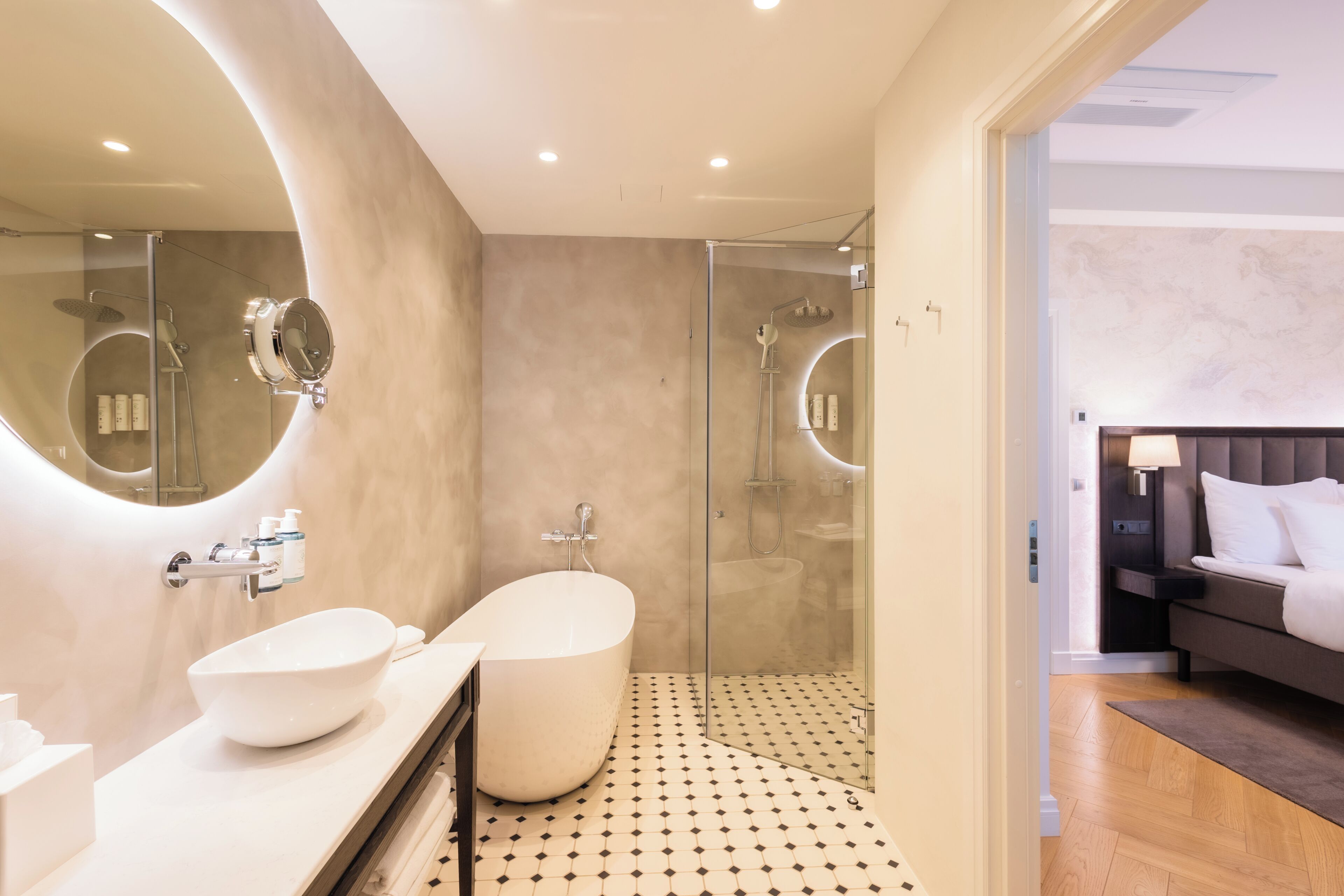 A modern bathroom with a freestanding bathtub, a glass-enclosed shower, and a vanity with a large mirror.