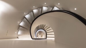 Un escalier en colimaçon moderne au design minimaliste, doté d’une rampe incurvée et d’un éclairage encastré.