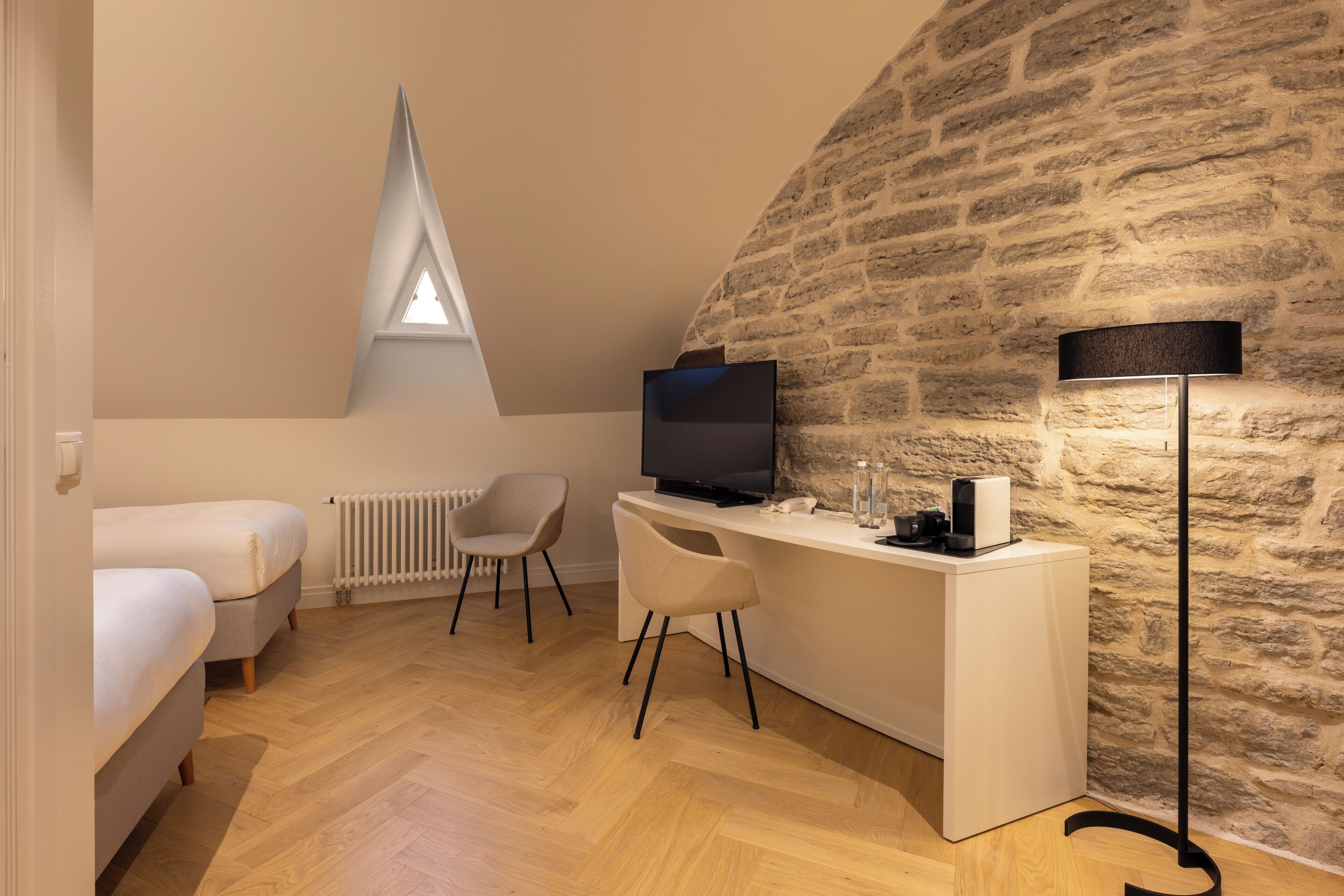 A cozy room with a loft bed, a desk with a computer, a chair, and a lamp.